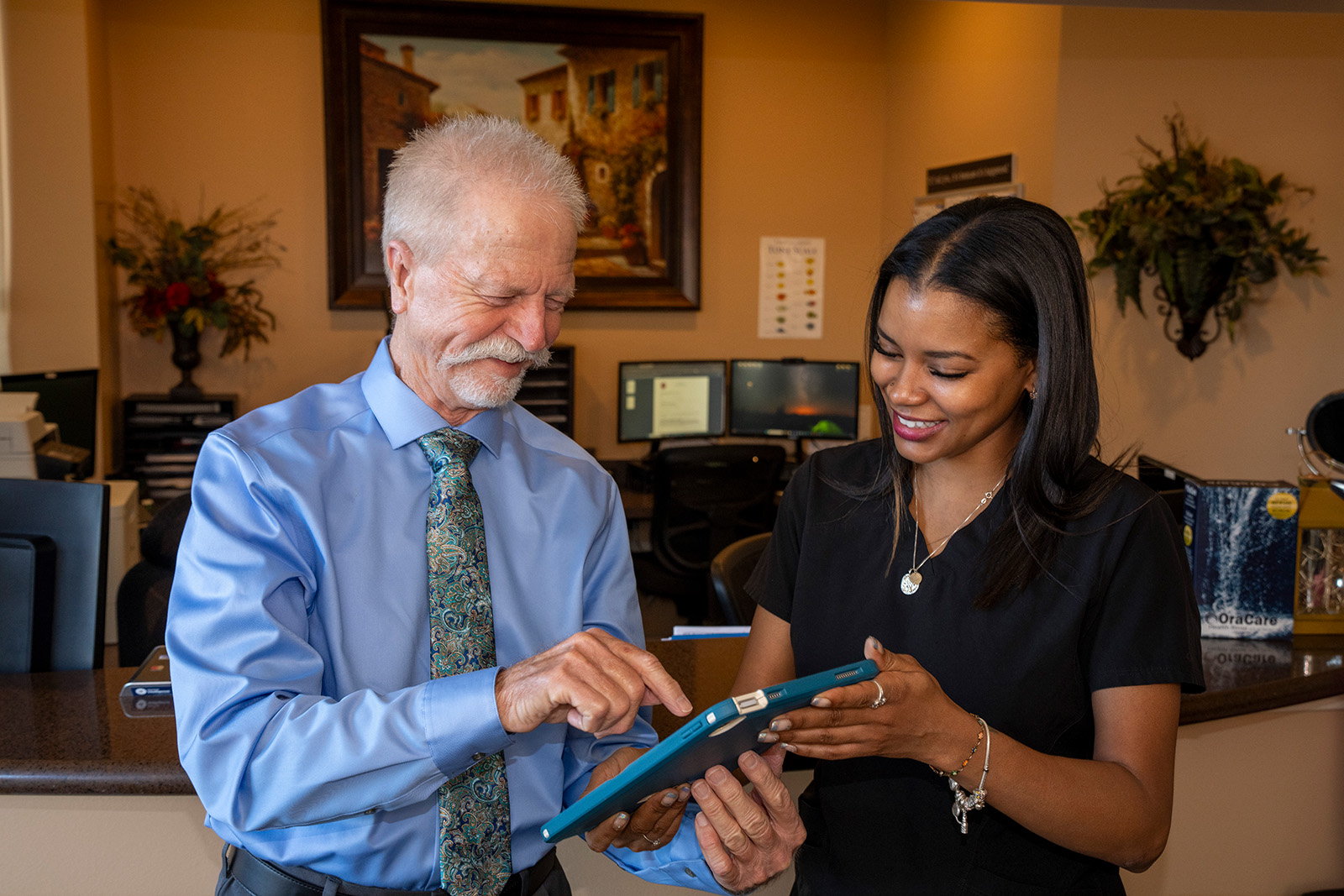 A patient and staff looking into a tablet and discussing payment options.
